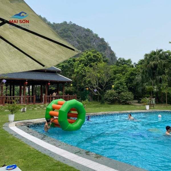 Bánh xe bơm hơi màu xanh cam trong bể bơi khu nghỉ dưỡng, trẻ em đang chơi cùng