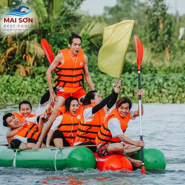 Nhóm nhân viên mặc áo phao chơi team building trên phao bơm hơi giữa mặt nước