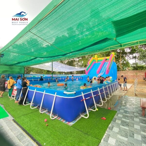 Cầu trượt bơm hơi đặt cạnh bể bơi lắp ghép tại khu vui chơi nước, đông trẻ em đang chơi