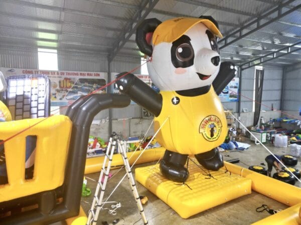 Linh vật gấu trúc bơm hơi mặc áo vàng thương hiệu MR.D.I.Y đang lắp đặt tại xưởng Mai Sơn